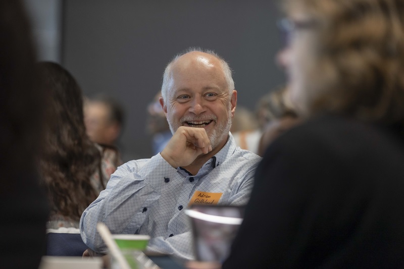 Man with beard sitting a table smiling