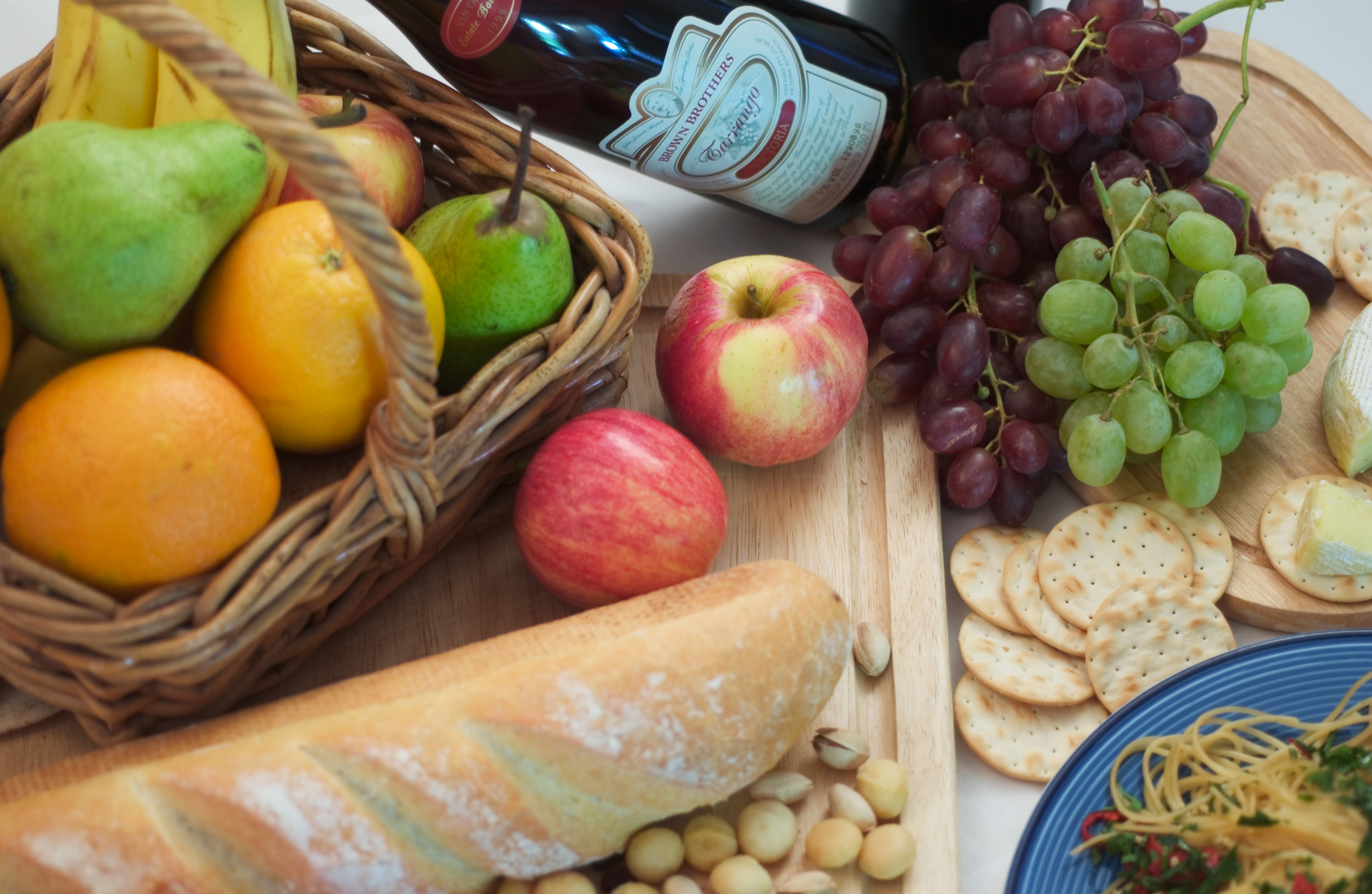 A variety of food including fruit, bread, crackers, and buts arranged randomly on a table