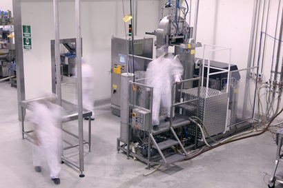 Two men working around the stainless steel high pressure processing equipment.