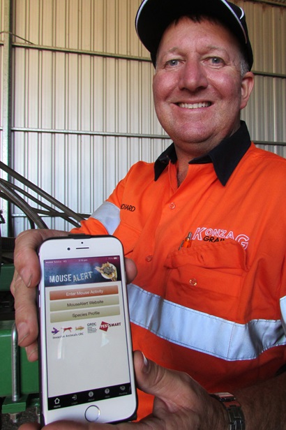 Grain grower Richard Konzag, of Mallala in South Australia, holding his mobile phone and displaying the MouseAlert app.
