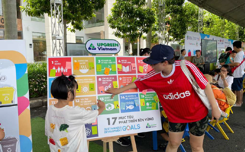 A mother and daughter stand in front of an interactive board outlining the UN's Sustainable Development Goals