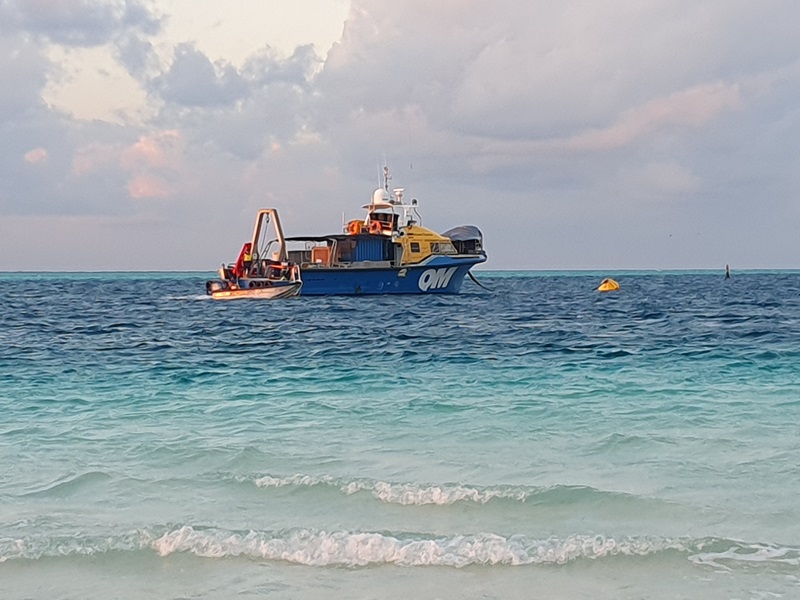 Boat anchored near the coast, sitting in the waves. 