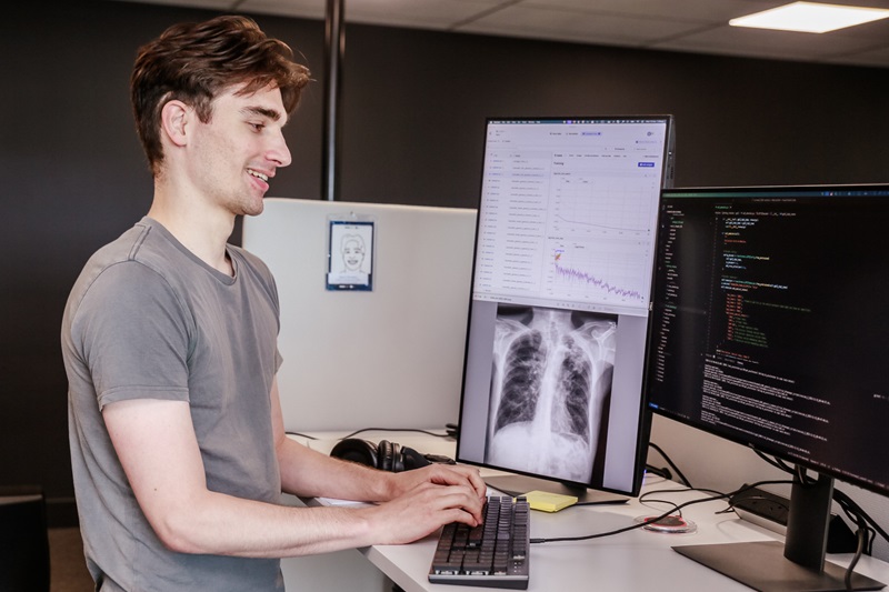 Man typing at computer at desk, with smile on face