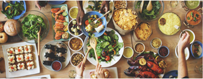 the image is an overview of food on a table with the hands of people serving some of the foods. there are salads, seafood and curries in with condiments laid out on the table on platters and in bowls and dishes. 
