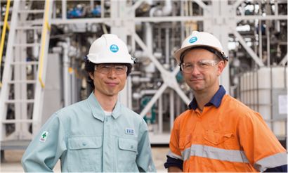 Two men smiling at camera in hard hats.