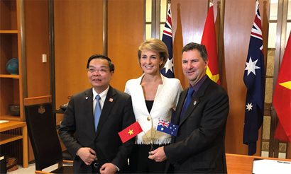 3 people standing in front of flags smiling