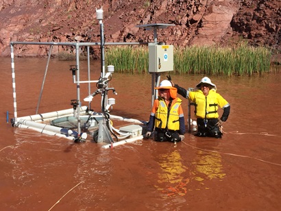 David McJannet and Aaron Hawdon standing with an Evaporation monitoring station in waist-high water.