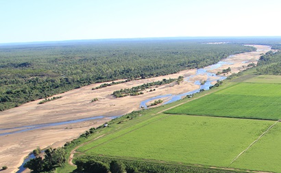 River with sandy banks with forest on one side and irrigated land on the other