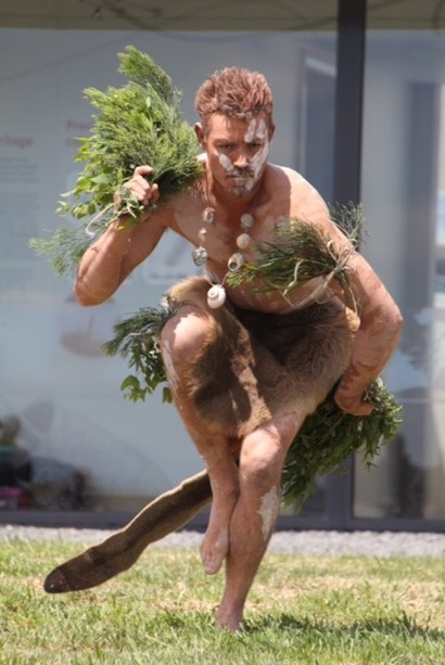 Person in traditional markings and clothing performing an Indigenous dance. 