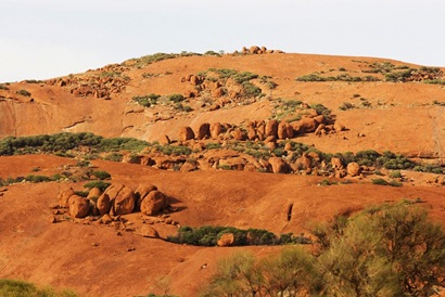 Part of the Musgrave Ranges on the Anangu Pitjantjatjara Yankunytjatjara (APY) Lands. Large boulders are pictured sitting on red earth and among scrub. The Musgrave Ranges are in the far north west of South Australia.