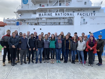 A large group of people standing on a wharf in front of a ship with Marine National Facility written on the side.