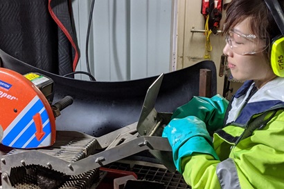 A person in safety glasses and hearing protection using a rock saw.