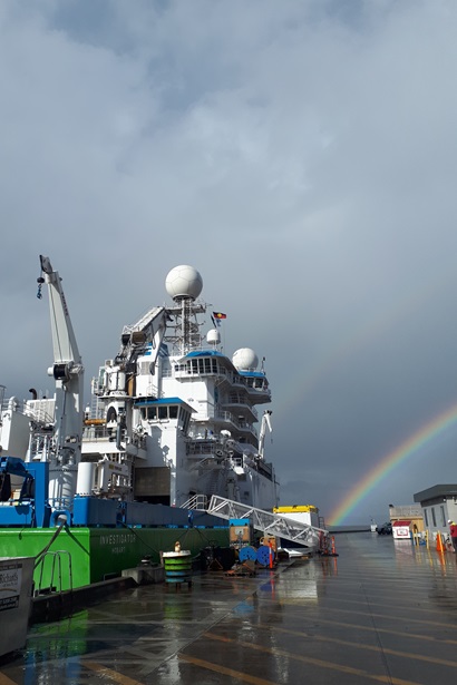 A ship tied up next to a wharf on a rainy day.