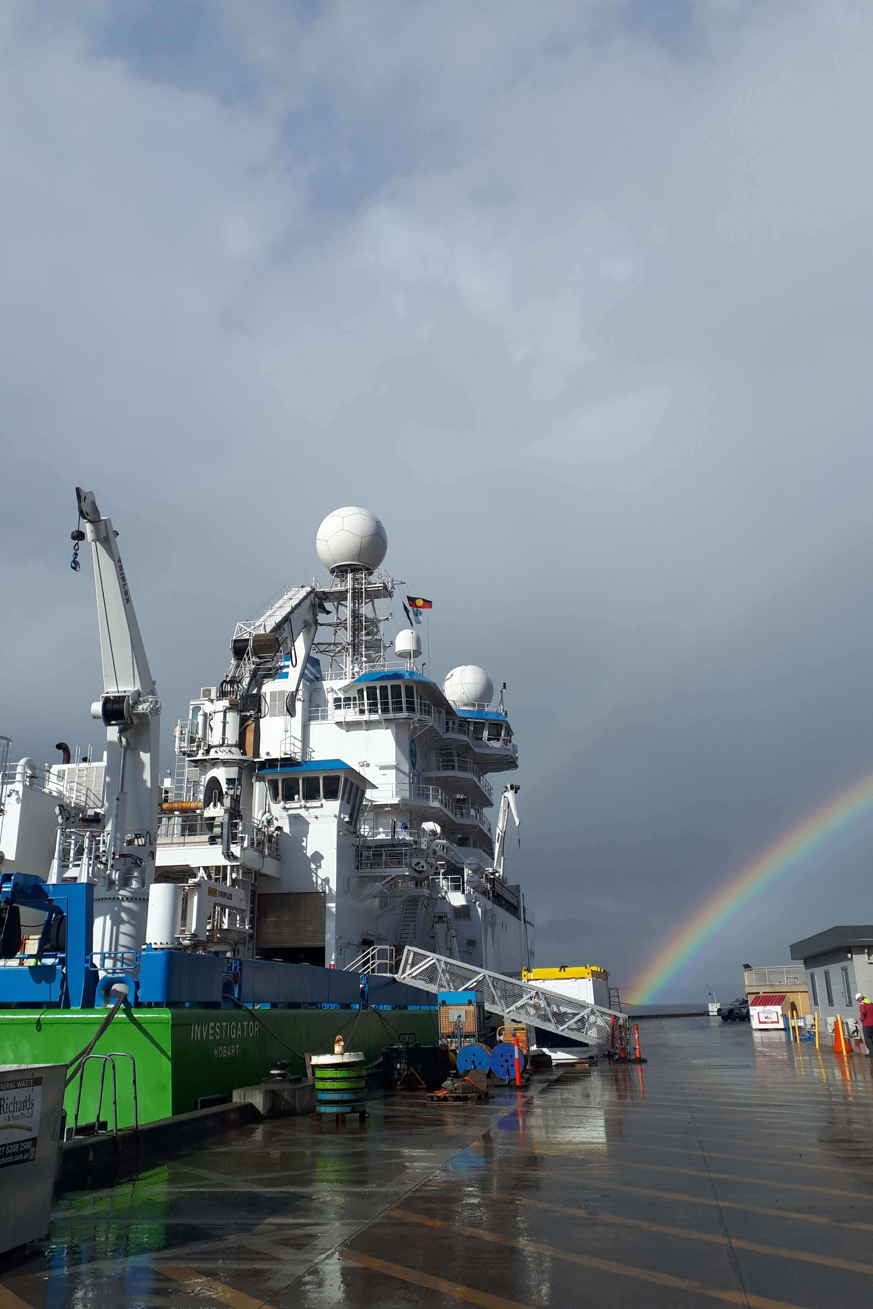 A ship tied up next to a wharf on a rainy day.