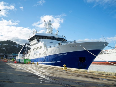 A blue and white research vessel at a wharf.