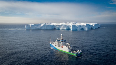 RV Investigator at sea with a mega-ice berg in the background.