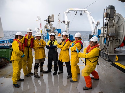 Seven members of the research team standing together on the deck of the ship.