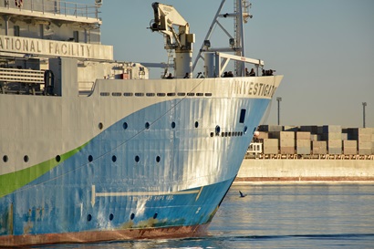 A close up of the bow of a ship with docks behind.
