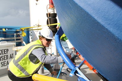 A person in hi-vis vest and hard hat looks at a large piece of scientific equipment.