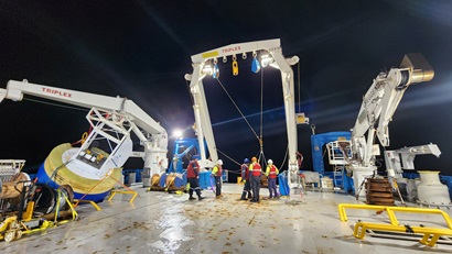 People working on the back deck of a ship at night.