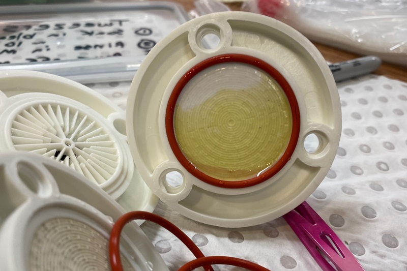 A close up view of a round plastic housing with a piece of filter paper on it.
