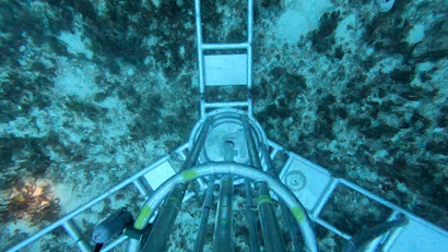 An underwater view of a piece of scientific equipment sitting on the seafloor.