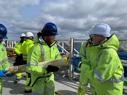 A group of people in hi-vis cold weather gear on a ship at sea.