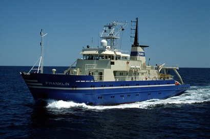 Blue and white ocean research vessel on the ocean.