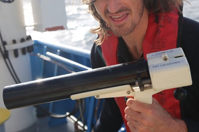 Scientists holding a gun-like launcher for piece of scientific equipment.