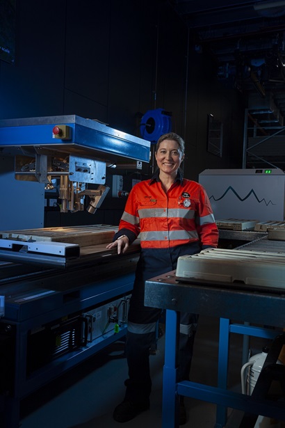 Female researcher stands beside scanning instrument