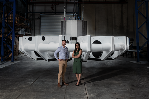 Man and woman standing in front of large circular white metal sensor unit