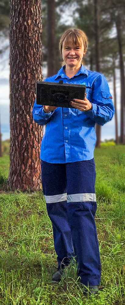 Female geologist standing in a greenfield holding a tablet device