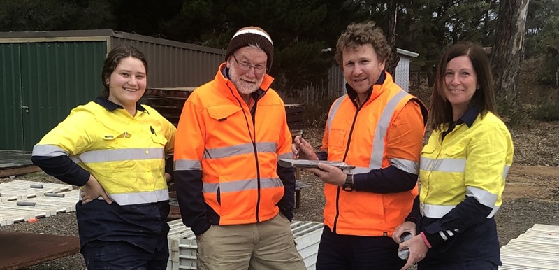 Four people in high-vis clothing gathered. Two males in orange high-vis clothing flanked by two females in yellow hi-vis clothing.