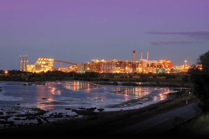Night photo of illunimated mineral processing plant with lake in foreground 