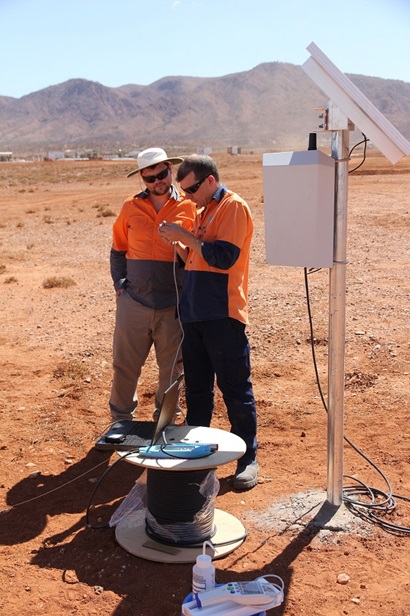 Two men standing in desert near monitoring equipment