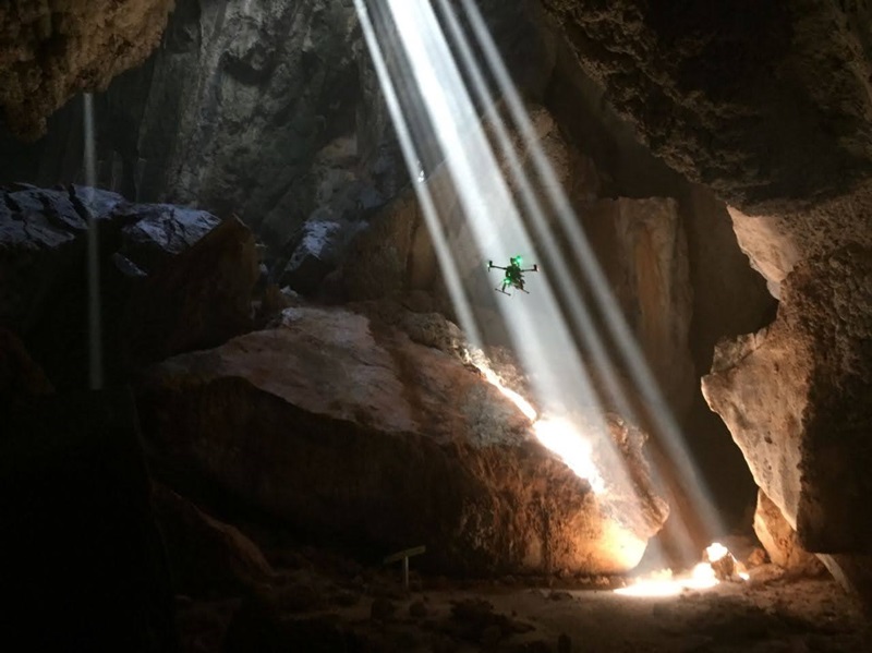 Drone entering shaft of light in cave