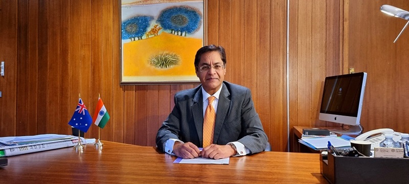Man sitting at desk displaying Indian and Australian flags
