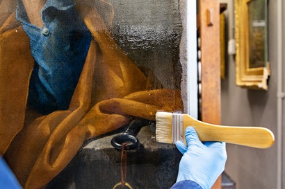 Hand applies a varnish resin onto a masterpiece painting with a thick soft brush