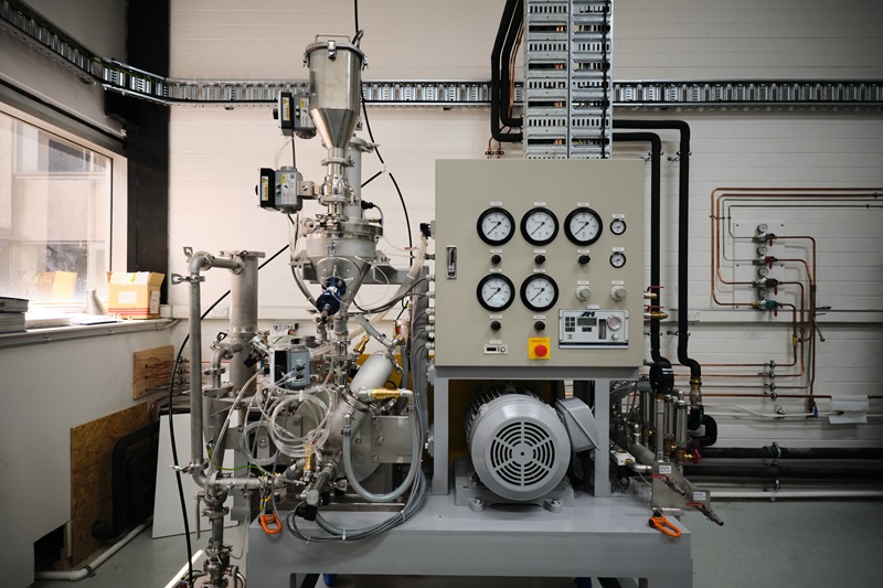 A large industrial metal powder processing machine with various knobs, tubes, fans and switches