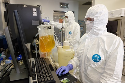 Two researchers in white hazmat suits working in a lab