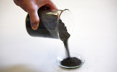 Titanium powder being poured from a beaker.