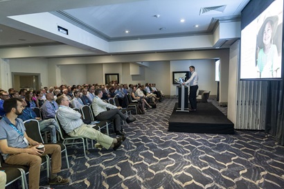 Man standing at a lectern facing a seated audience