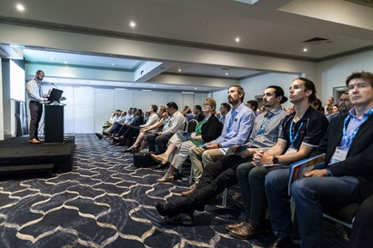 Seated audience gazing at standing man speaking