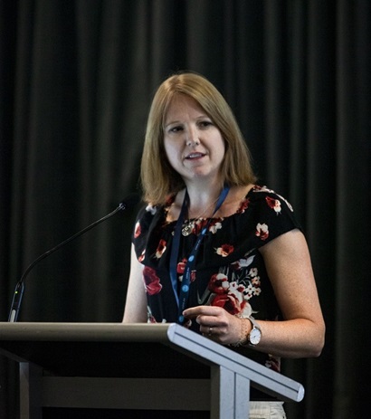 Red-haired woman speaking behind a lectern