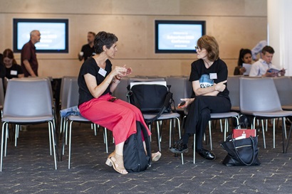 Two women sitting in seats talking and drinking tea