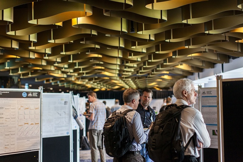 three man looking at a scientific poster