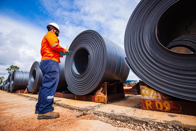 Man inspecting large rolls of steel