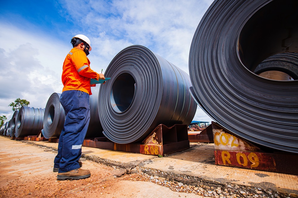 Man inspecting large rolls of steel
