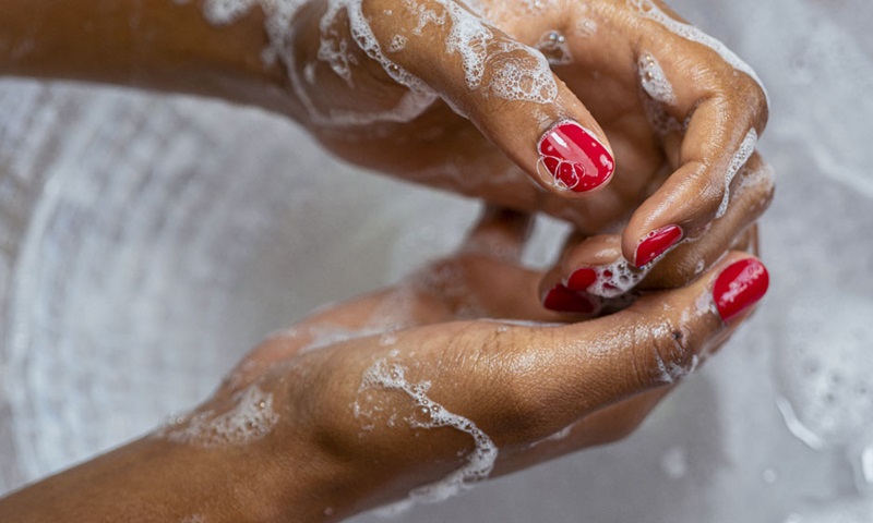 A close up of a woman washing her hands in soapy water