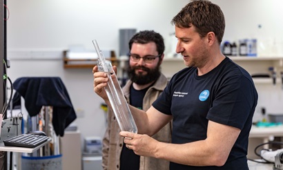 Two people looking at a glass instrument in a laboratory.